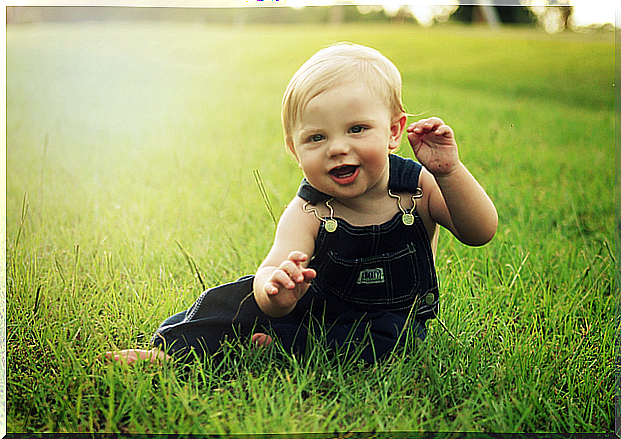 The child is sitting on the lawn